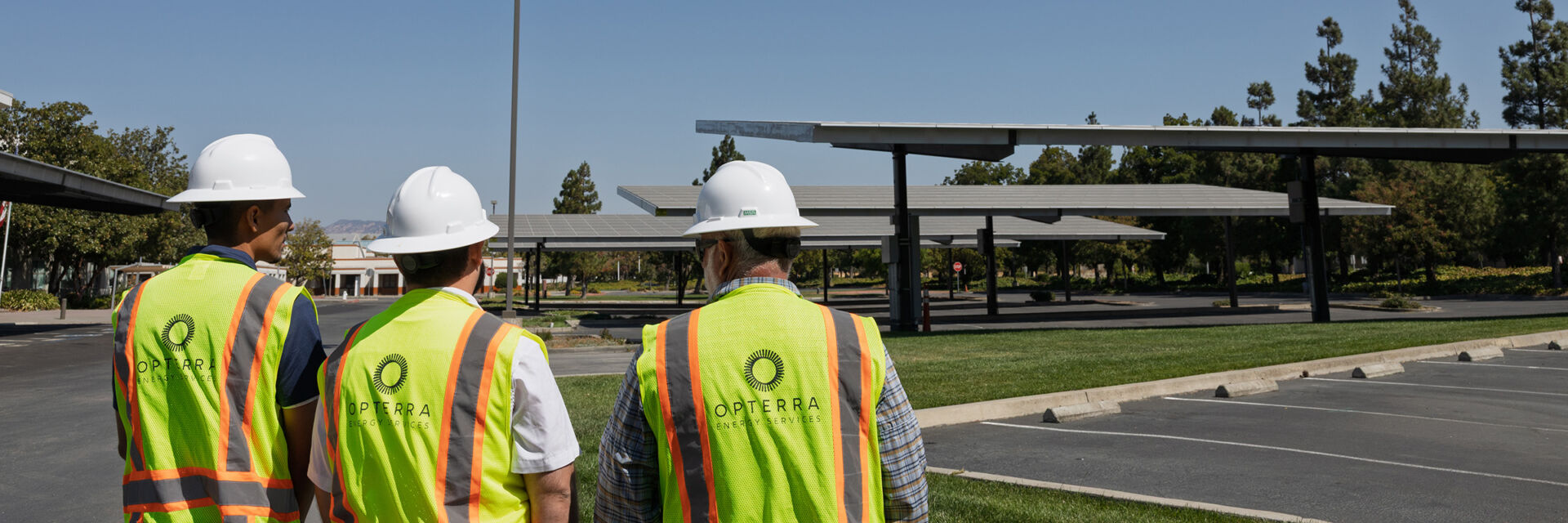OPTERRA employees wearing protective equipment on a project site with parking solar canopies installed